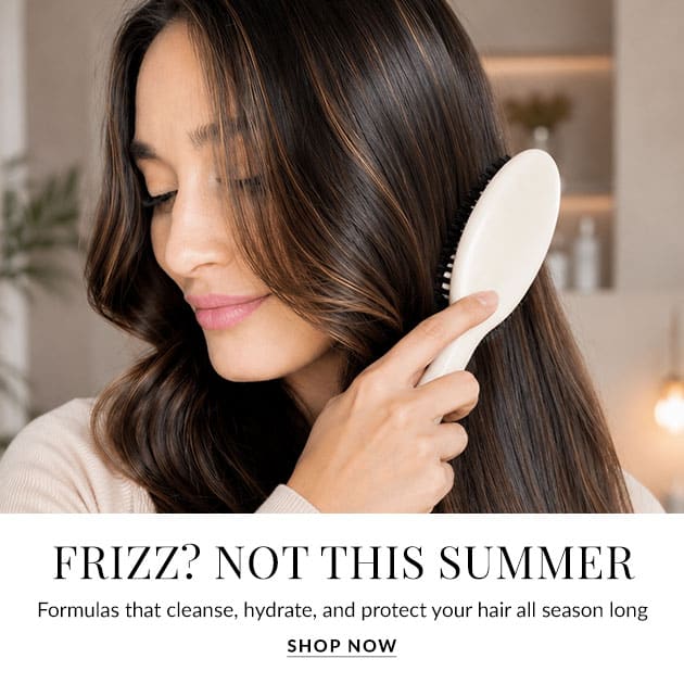 Woman brushing long hair with a white detangling brush in a soft, neutral setting; overlay text reads 'FRIZZ? NOT THIS SUMMER' with a 'Shop Now' prompt.