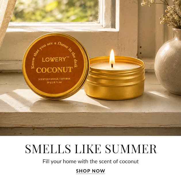 Coconut-scented candle in a gold tin, lit, on a windowsill with the caption 'Smells Like Summer'.